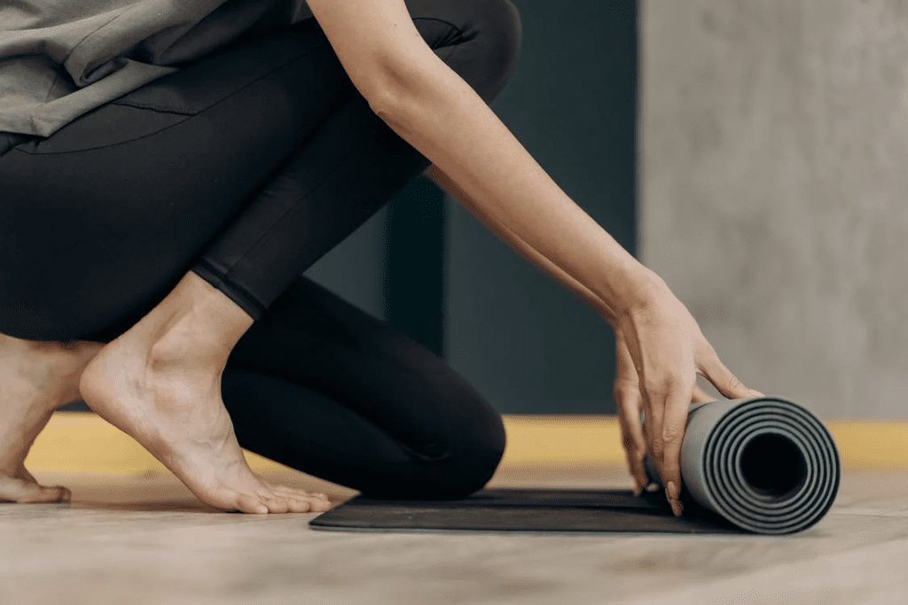 woman unrolls her yoga mat, preparing for a rejuvenating practice.