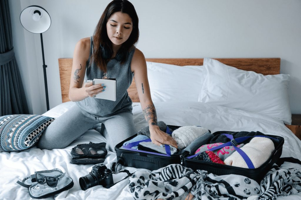 Woman sitting on a bed wearing a gray tank top.