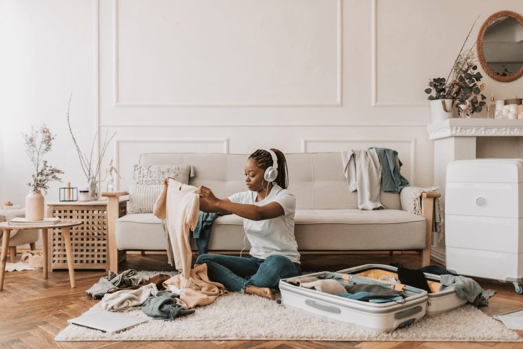 Woman wearing headphones while packing her suitcase.