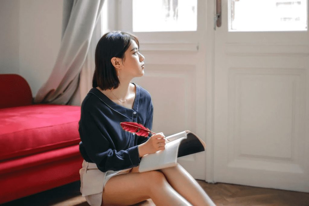 A thoughtful woman writing in a notebook at home