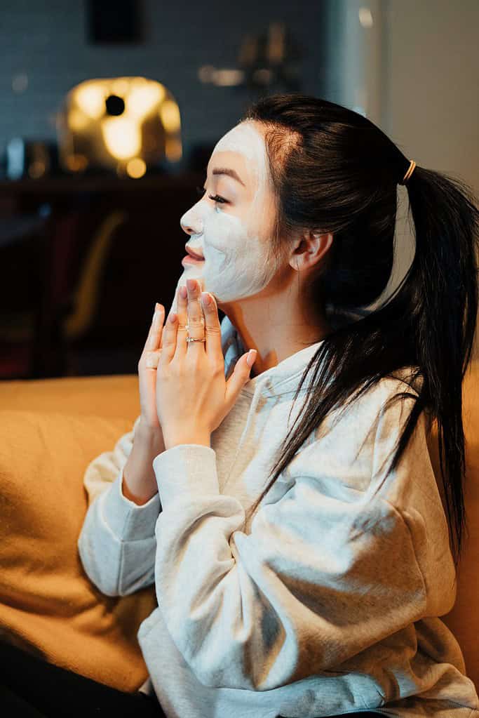 a woman putting white cream to her face