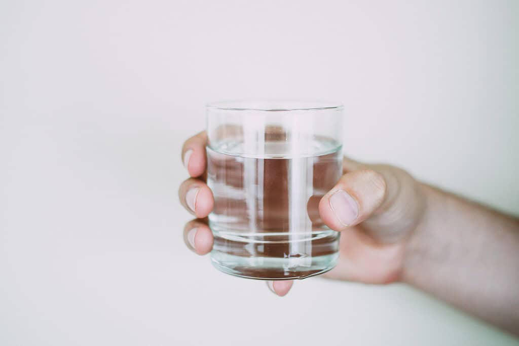a glass with water held by a person