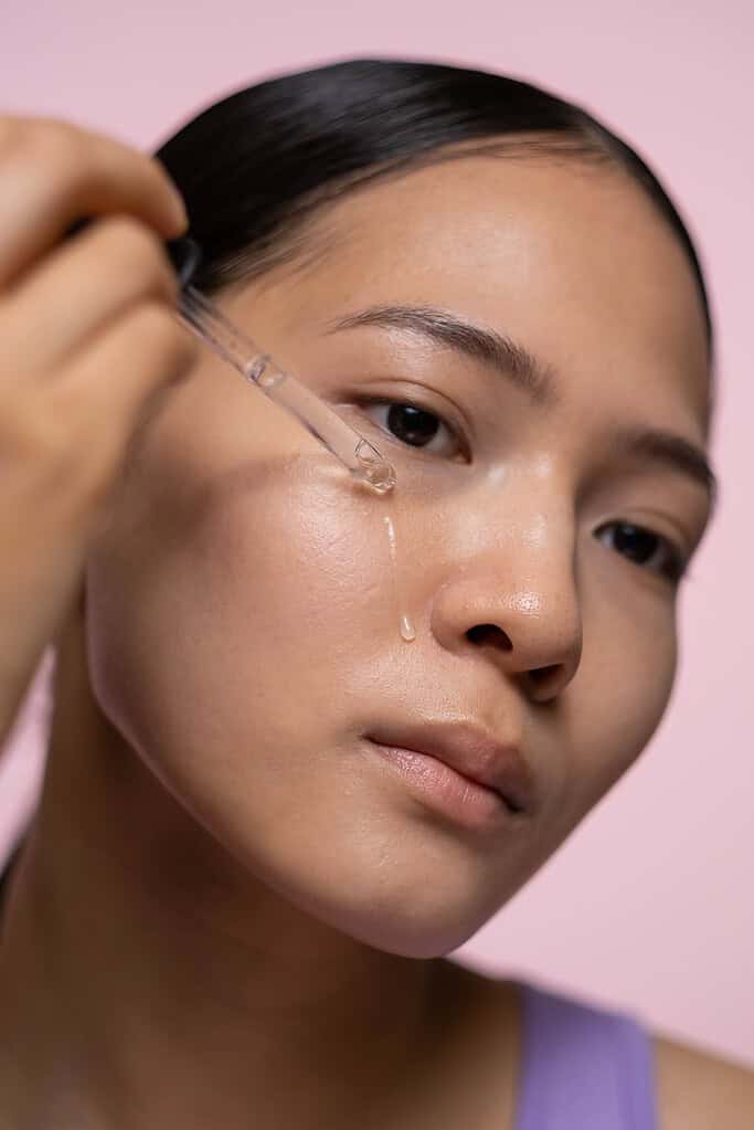 a woman putting serum on her face