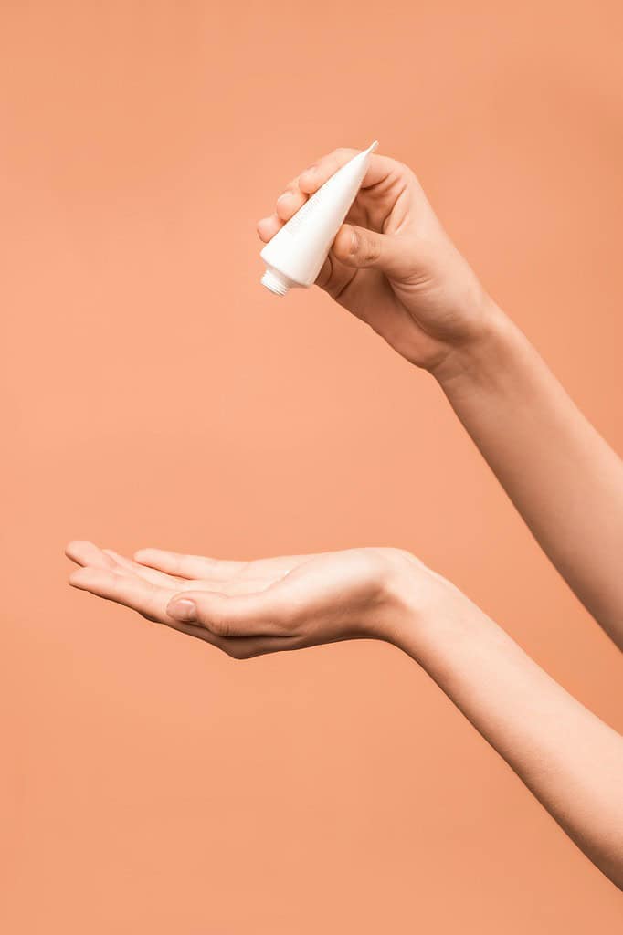 a person pouring cream on their hand