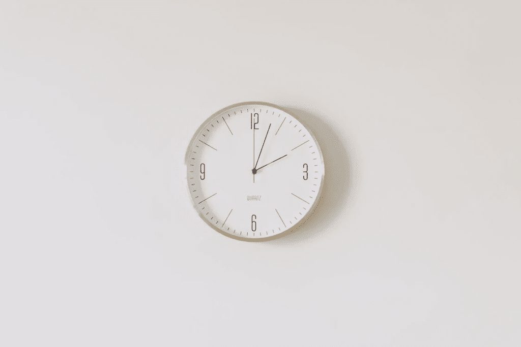 Round analog wall clock with gold trim on white wall