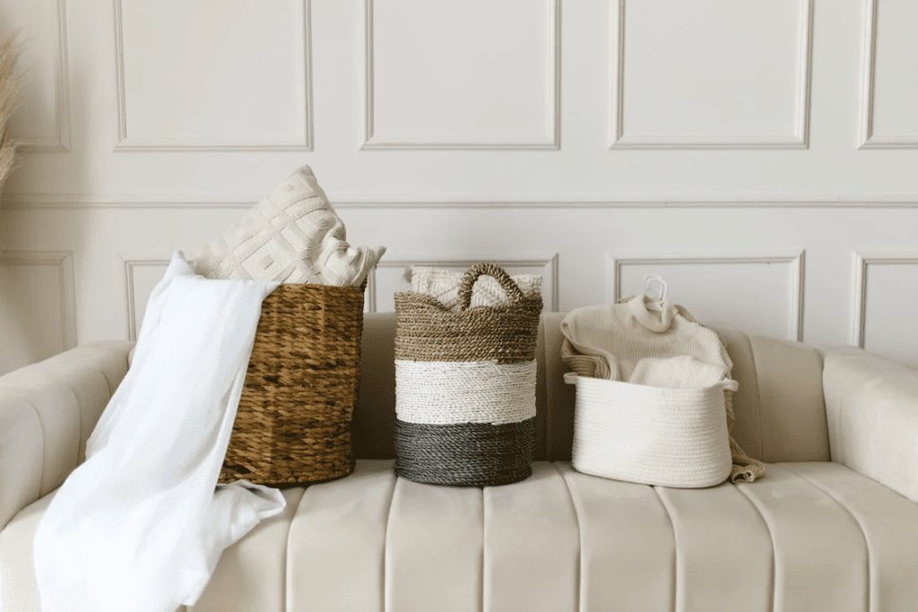 Clothing items separate inside the three woven baskets on a sofa