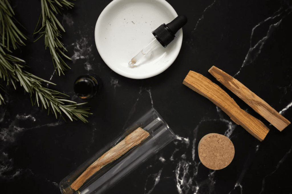 Glass pipette with aromatic oil on a plate, alongside rosemary branches.