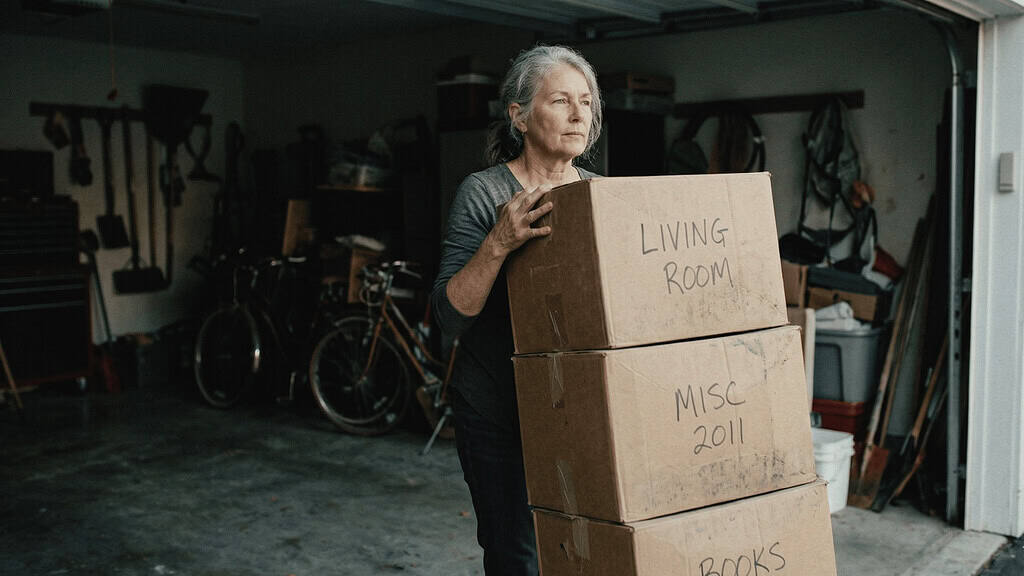 A lady in the garage holding a stack of boxes from their last move