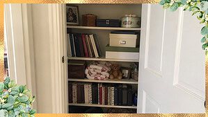 An open hall closet holding shelves of saved keepsakes, old boxes, and photo albums, full but not chaotic, in warm daylight