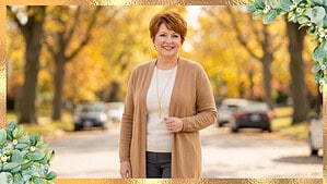 Woman in a fine knit top and open neutral longline cardigan with a long pendant on an autumn street, with open space for a title.