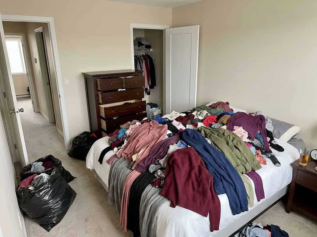A bed piled high with dumped-out clothes and half-filled bags in the hall, the exhausting big decluttering purge