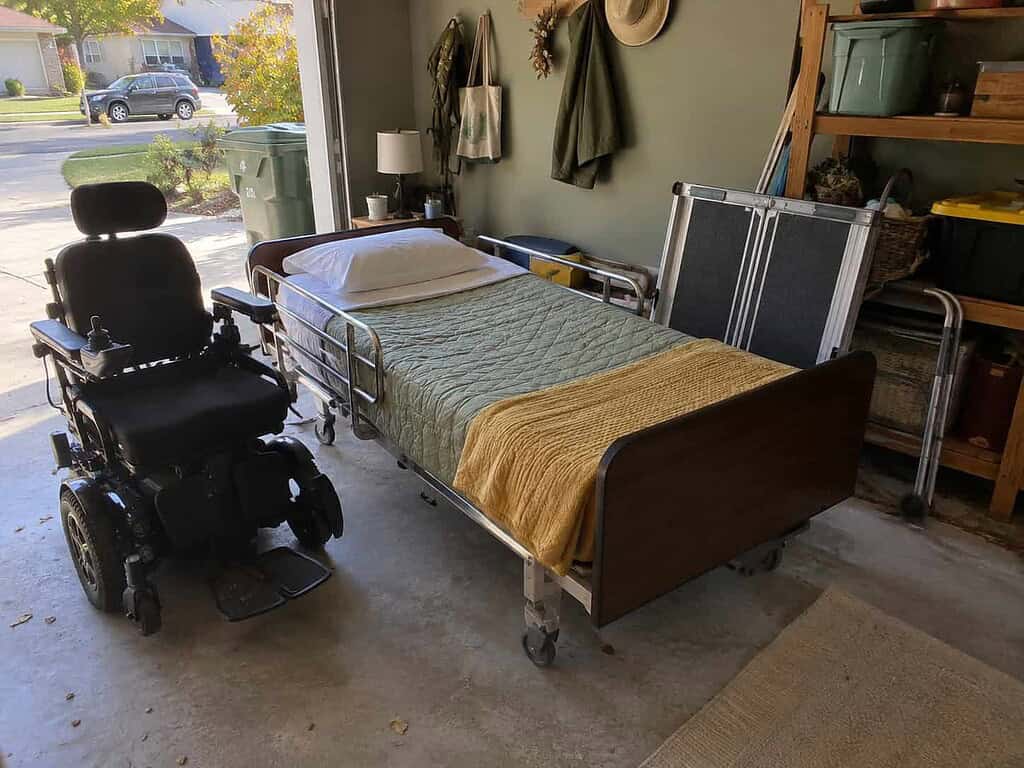 A hospital bed and power wheelchair set near an open garage door, clean and ready for a charity pickup