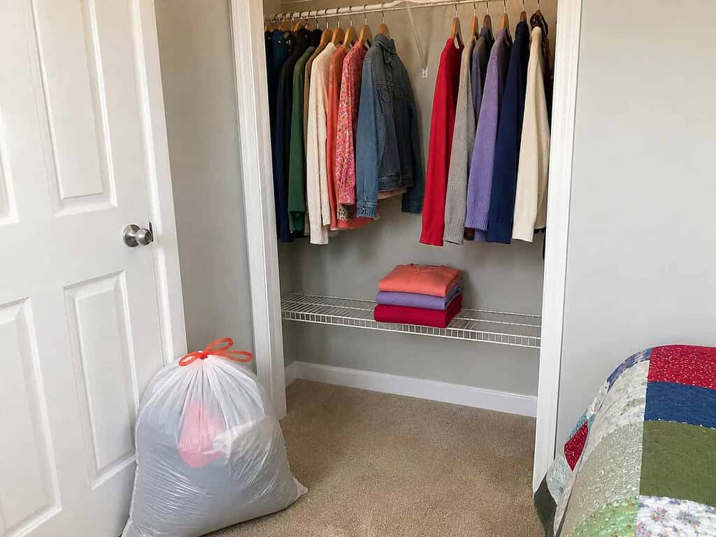 A calm, cleared closet with a tidy shelf and one donation bag by the door, proof a small imperfect start was enough
