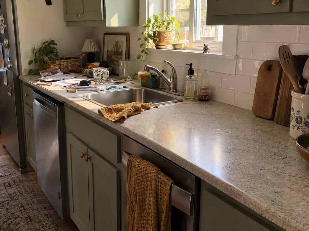 A kitchen counter half cleared, one side still scattered with mail and the other wiped bare