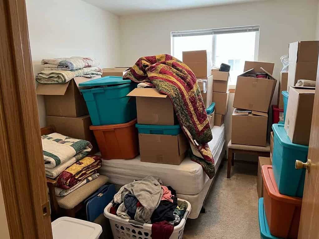 A crowded spare room full of boxes and stored belongings, showing how holding on can quietly turn into weight