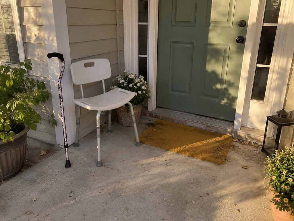 A clean cane and shower chair set out on a front porch, ready for a neighbor to pick up