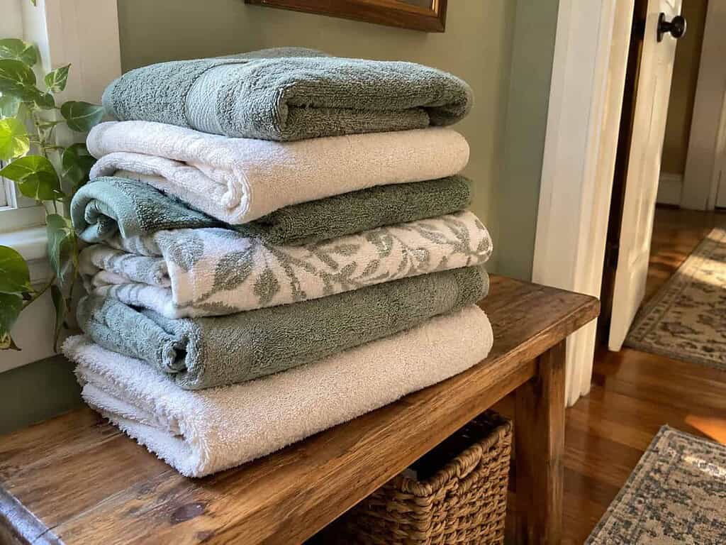 A small tidy stack of about six soft folded bath towels on a wooden bench