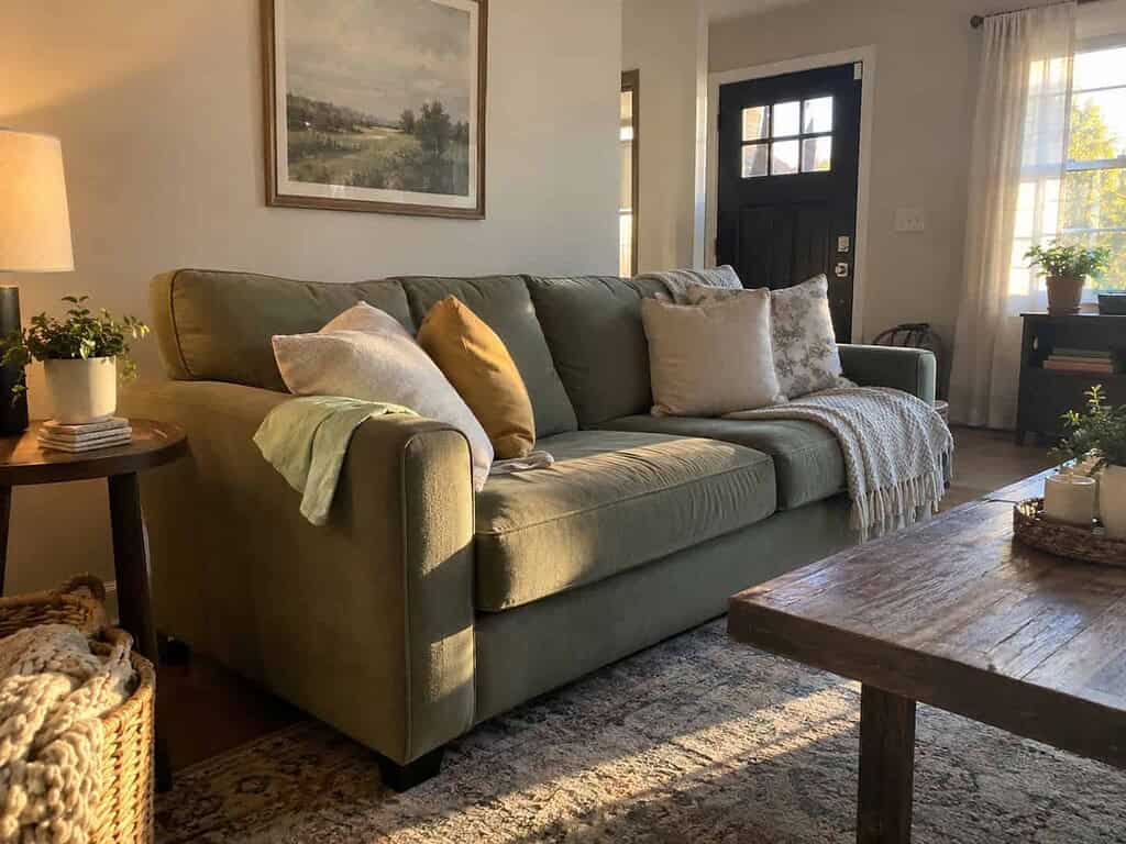 A freshly tidied living room with plumped pillows, a folded throw blanket, and a clean side table