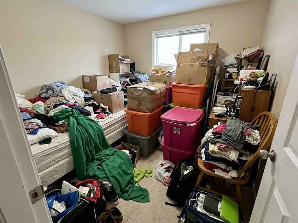 An overstuffed spare room piled with boxes and clothes, how all-or-nothing thinking keeps the clutter