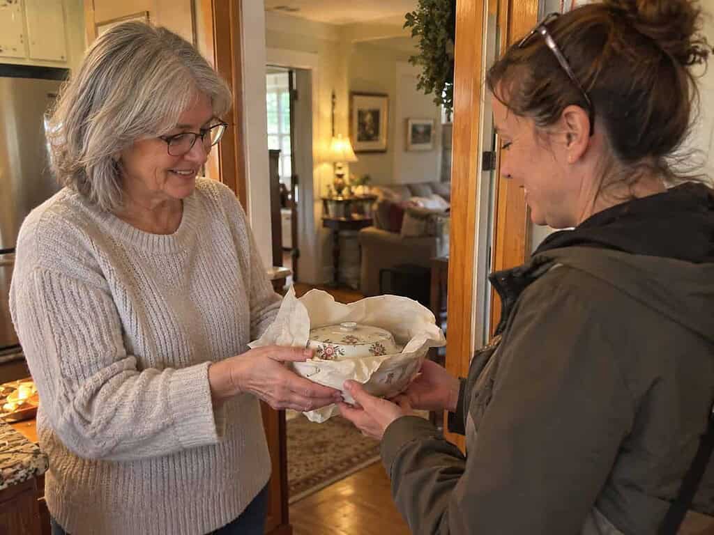An older woman handing a wrapped old dish to a younger woman who's glad to receive it