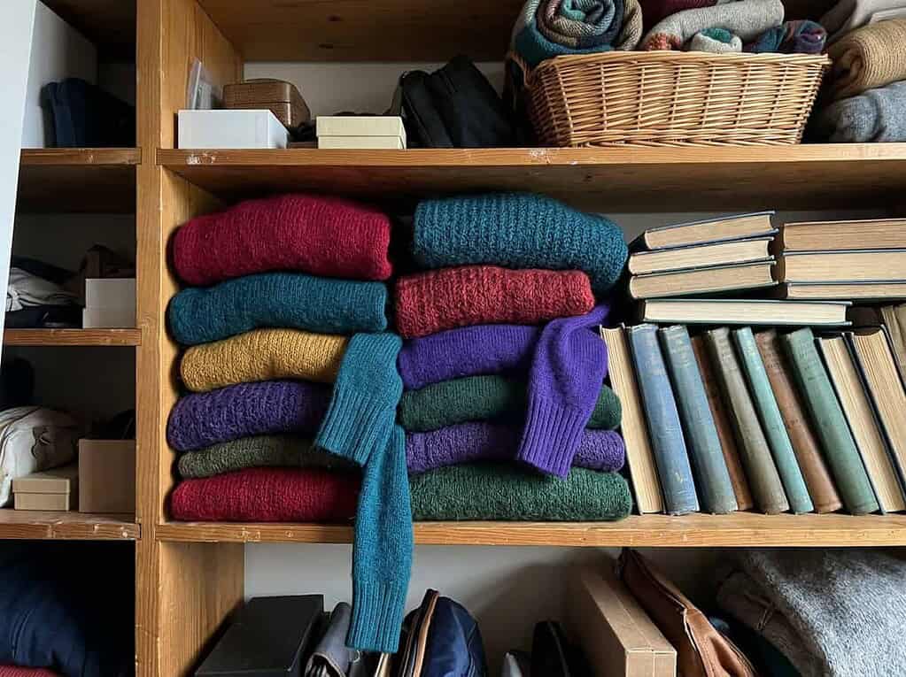 A closet packed with colorful folded sweaters and stacked books, the belongings we hold on to more tightly when lonely