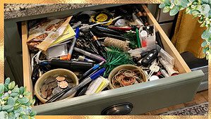 An overflowing kitchen junk drawer crammed with pens, keys, batteries, and odds and ends, so full it can barely close