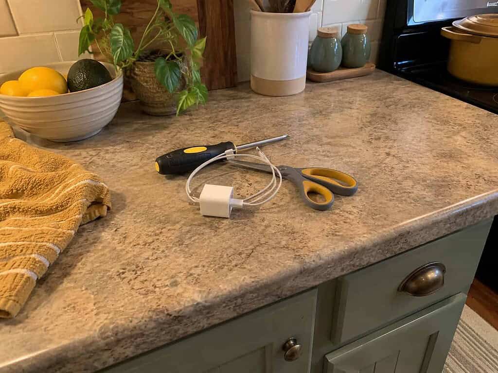 A small pile of misplaced items, a screwdriver, a charger, and scissors, set aside to return to their real homes