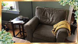 A cozy armchair and side table holding a mug, mail, and remote, the starting point for micro decluttering by putting away five things