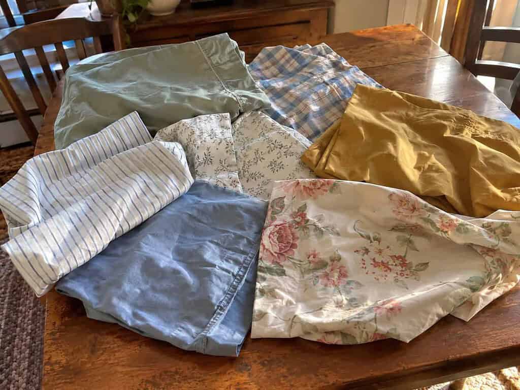 A jumble of mismatched single pillowcases with no matching pairs spread on a table