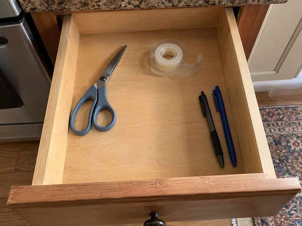 An open kitchen drawer with scissors, tape, and pens each in their own spot and room to spare