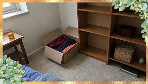 An open donation box beside one half-cleared shelf in a calm room, the small steady pace of slow decluttering