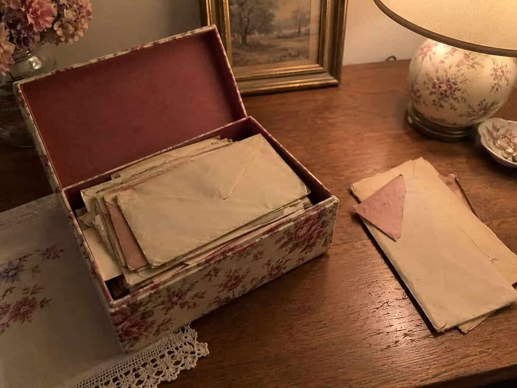 A small keepsake box holding a chosen stack of old letters with a few set aside nearby to let go