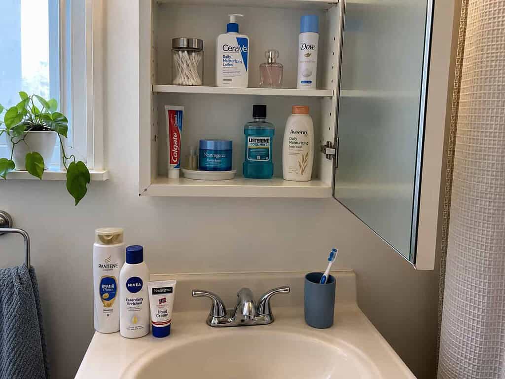 An open medicine cabinet with a couple of old bottles set out to toss, an easy place to start decluttering