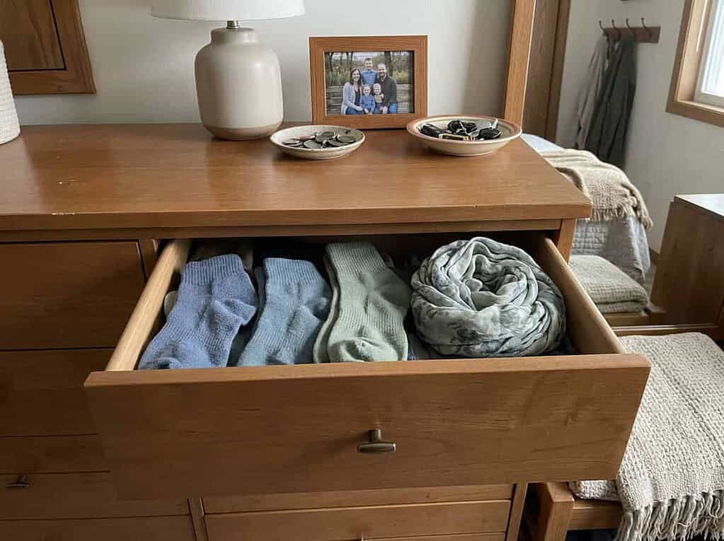 One small dresser drawer being tidied in a warm bedroom, showing you never have to declutter the whole house