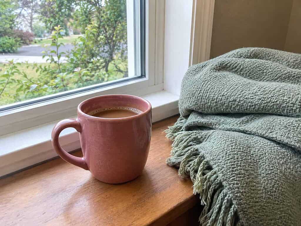 A calm mug of coffee by a sunny window with a folded throw, choosing peace over the fight