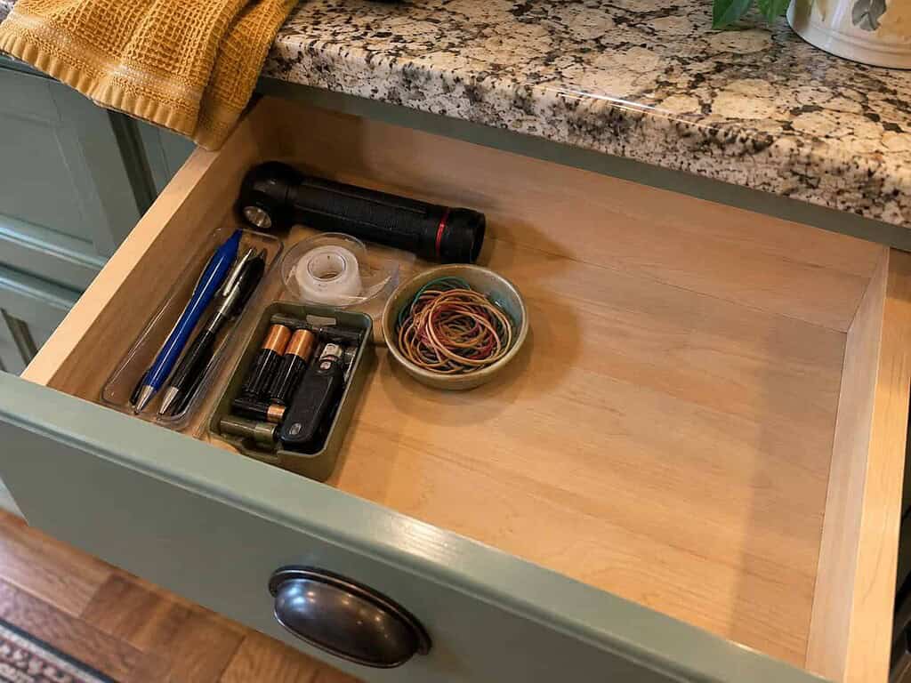 A tidy junk drawer holding only a few useful items, good pens, a flashlight, batteries, and tape, with open space