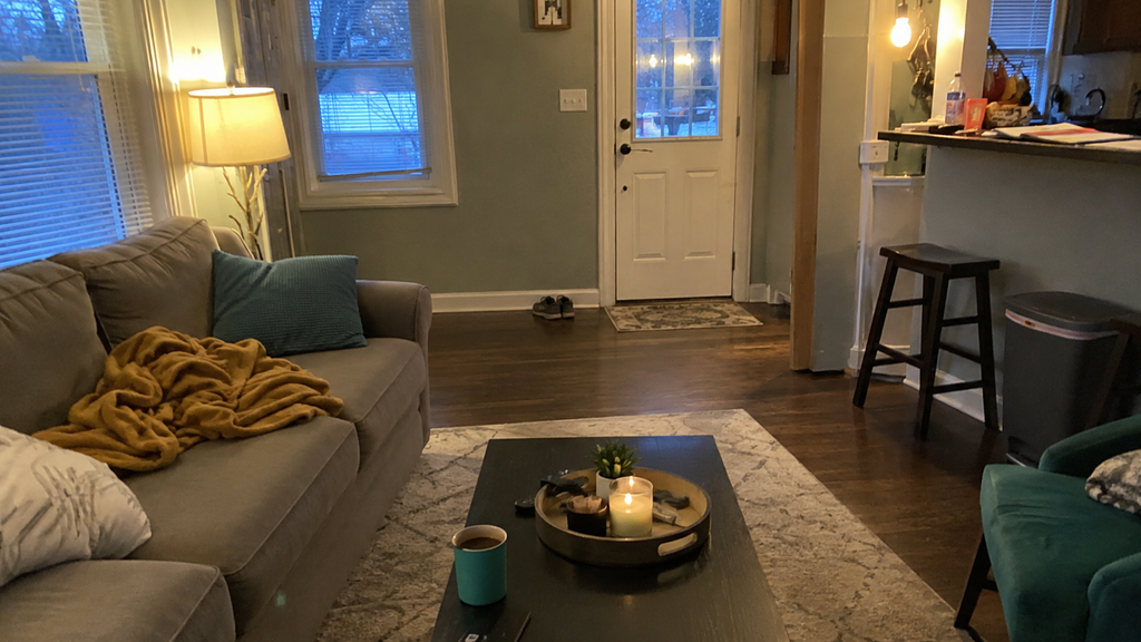A lived-in living room in the evening with a bunched blanket, mail on the counter, and shoes by the door, the kind of tired-day mess micro decluttering helps with