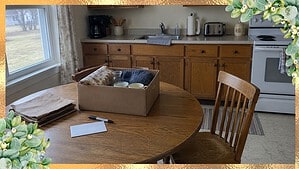 Paper grocery bags, a marker and a box of things to give away on a kitchen table