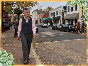 Woman with a short silver pixie in a navy tweed vest, pink satin blouse and gray trousers walking on a Georgetown street in fall