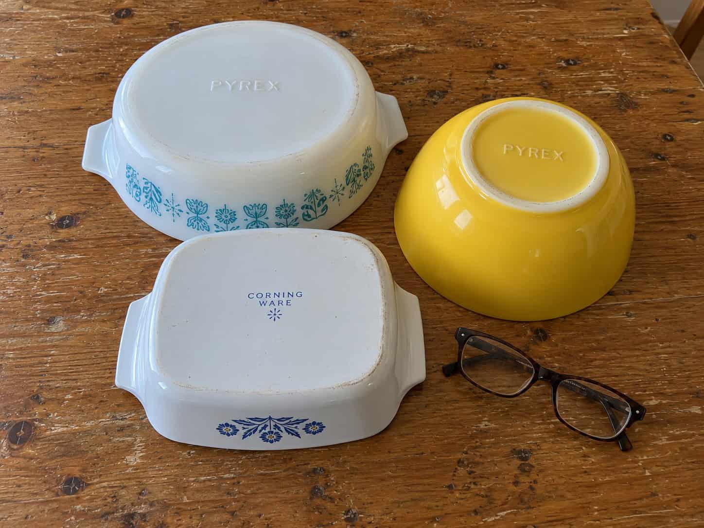Pyrex and Corning Ware dishes turned upside down on a table to show the brand names on the bottom