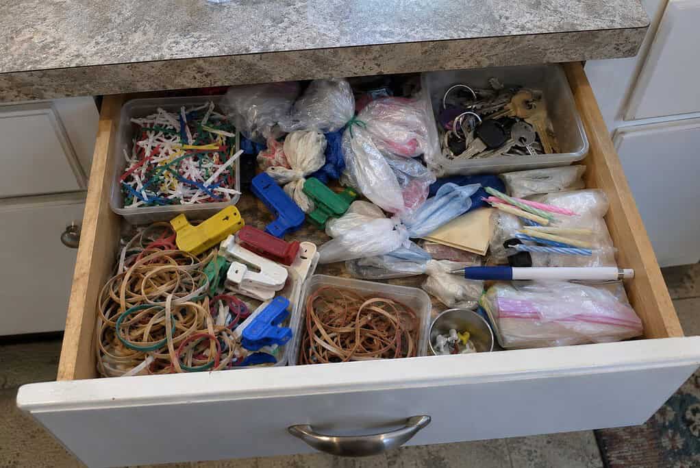 A kitchen drawer crammed with saved twist ties, bread clips, rubber bands, old keys and plastic bags